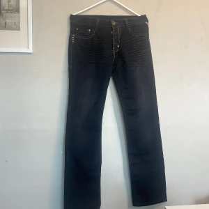 Mörkblå jeans från Jack & Jones - Snygga mörkblå jeans från Jack & Jones med raka ben och kontrastsömmar. Klassisk femficksmodell med dekorativa nitar och detaljerade bakfickor. Perfekta för en avslappnad stil.