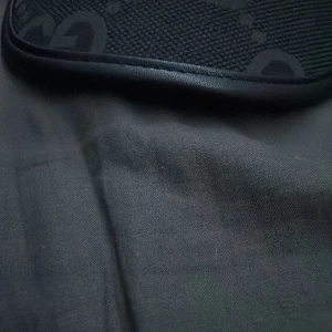 Svart axelväska från Guess - Säljer en svart axelväska från Guess med diskret logomönster och detaljer i syntetmaterial. Väskan har en stilren design och passar perfekt för dig som gillar klassiska accessoarer.