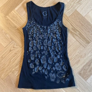 Linne Guess - Ett svart linne från guess med leopardmönster och stenar. Den har ett par mindre hål, syns inte så mycket och jag kan laga om så önskas.