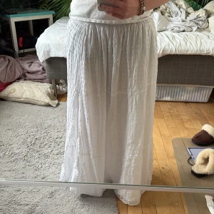 Vit långkjol från Bershka - Säljer en luftig och flowy vit långkjol från Bershka. Kjolen har resår i midjan och är gjord i ett tunt, lätt material med lite struktur. Perfekt för varma dagar och enkel att styla med olika toppar.