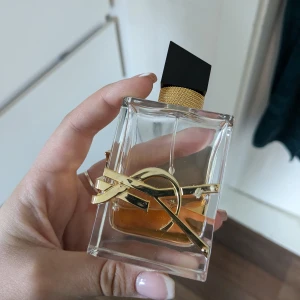 Yves Saint Laurent Libre Eau de Parfum - Säljer en lyxig parfym från Yves Saint Laurent, Libre Eau de Parfum. Flaskan är rektangulär i genomskinligt glas med guldiga detaljer och en svart asymmetrisk kork. Doften är elegant och modern med inslag av lavendel och apelsinblom.