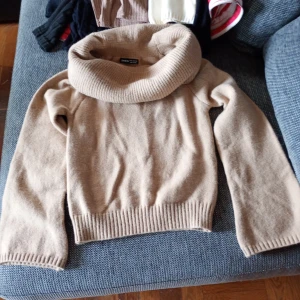 Beige stickad polotröja från Zara Knit stl M - Mysig beige stickad polotröja från Zara Knit med bred, vikt krage och långa ärmar. Tröjan har ribbade muddar och är tillverkad i en mjuk ull- och kashmirblandning. Perfekt för kyliga dagar.