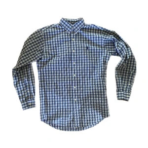 Blårutig skjorta från Ralph Lauren - Säljer en klassisk skjorta från Ralph Lauren med knappar framtill och broderad logga på bröstet. Skjortan är i bra skick och i storlek S. Hör av dig vid fundering!