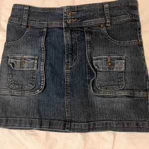 Jeanskjol med fickor och bälte från Flash - Säljer en klassisk blå jeanskjol från Flash med två stora fickor framtill och dekorativa knappar. Kan justeras i baksidan med bälten. Tyvärr vet jag inte vad det är för storlek men passar mig som brukar använda XS/S. ❤️