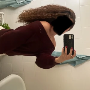 Vinröd offshoulder stickad tröja - Mysig vinröd stickad tröja med offshoulder-design och långa ärmar. Perfekt för att skapa en avslappnad men ändå trendig look. Tröjan har en lös passform och är superbekväm att bära.