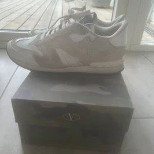 Valentino Rockrunner  - Säljer ett par Valentino Rockrunner sneakers i beige och vitt med camouflage-mönster. Skorna har snörning, rund tå och detaljer i mocka och skinn. Klassisk Valentino-logga på plösen och nitar på hälen. Kommer med originalkartong. Och kvitto, priset är inte hugget i sten vid snabb affär så kan jag sänka 
