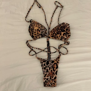 Leopardmönstrad bikini med snörning - Säljer en trendig leopardmönstrad bikini/badräkt  med flera smala snören och cut-out detaljer. Den har trekantsformade kupor och högt skuren underdel. Materialet är mjukt och stretchigt för en bekväm passform.