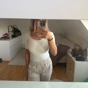 Vit bodysuit - Säljer en vit bodysuit med korta ärmar och rundad halsringning från Gina Tricot i storlek S, aldrig använd