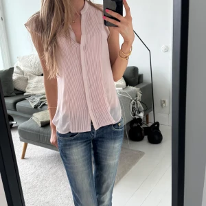 Ljusrosa blus från H&M - Säljer en ljusrosa blus från H&M med knappar framtill och fina veckade detaljer på bröstet. Blusen är ärmlös och har en lätt och luftig känsla, perfekt för varmare dagar.💓🥰 