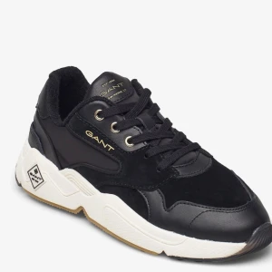Svarta sneakers från Gant - Snygga svarta sneakers från Gant med detaljer i mocka och skinn. Skon har snörning, vit platt sula och diskreta guldiga logotyper. Perfekt för en sportig och stilren look.
