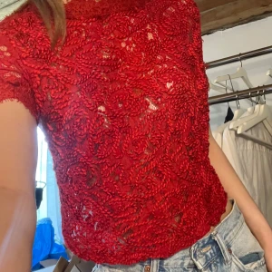 Röd spetsblus - Säljer en röd blus i spets med korta ärmar och rund hals. Blusen har ett vackert blommigt mönster och är något genomskinlig. Skriv från frågor❤️❤️
