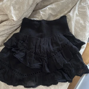 Svart volangkjol från Neo Noir - Supersöt svart kjol från Neo Noir med bred smock i midjan och flera lager volanger. Använd 1-2 gånger så är som ny! Står ingen storlek men passar xs-m