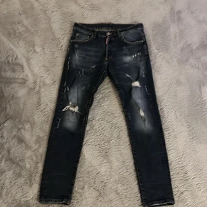 Svarta slitna jeans från Dsquared2 - Säljer ett par svarta jeans från Dsquared2 med slitningar och dem är äkta köpta för 2 år sen och dem har blivit för små.