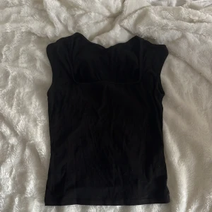 Svart ärmlös topp från Gina Tricot - Säljer en svart, ärmlös topp från Gina Tricot. Toppen har en enkel och stilren design med rundad halsringning och figurnära passform. Perfekt att matcha med jeans eller kjol för en snygg look. Användt två gånger så den är i väldigt bra skick💕