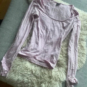 Ljusrosa långärmad topp - Säljer en ljusrosa långärmad topp med bred, rundad urringning. Tunn och mjuk i materialet, perfekt för lager-på-lager eller som den är. Enkel och stilren design som passar till mycket.
