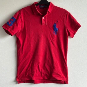 Ralph Lauren - Röd pikétröja från Polo Ralph Lauren med blå broderad logga på bröstet och en blå siffra 3 på ärmen. Storlek S, Mycket bra skick. Hör av dig vid funderingar!