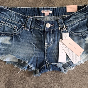 Xtra low denim shorts Gina Tricot - Eftertraktade 14+ xtra low jeansshorts från Gina Tricot med extra låg midja. Modellen har slitna detaljer, fransig kant och klassiska fickor fram och bak. Helt nya med lappar och inplastade 😊