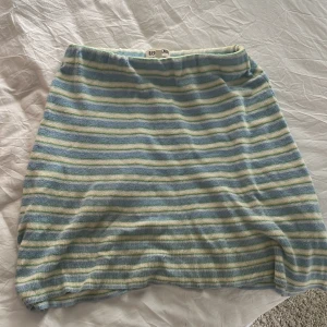 Randig kjol från Djerf Avenue - Superfin kort kjol från Djerf Avenue i mjukt stickat material. Kjolen har blå, gröna, vita och gula ränder och en elastisk midja som gör den bekväm och enkel att bära. Perfekt för dig som gillar färg och vill ha en chill vibe.