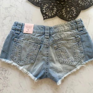 Slutsålda Lågmidjade jeansshorts Gina  - Snygga ljusblå lågmidjade jeansshorts från Gina. Perfekta för sommaren och en avslappnad look. Ny med prislappen kvar 