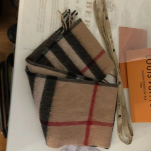 Beige rutig halsduk från Burberry - Säljer en as fet burberry scarf som är perfect till alla väder - helt ny oanvänd - inga defekter på den - ingen parfym lukt eller typ av parfym märke / fläck - kommer med allt og 