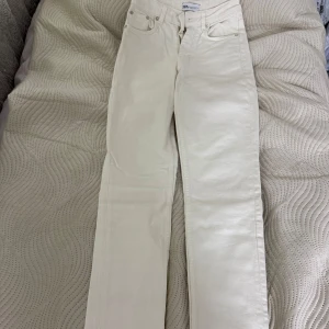 Vita raka jeans från Zara - Snygga vita jeans från Zara med raka ben och klassisk femficksdesign. Byxorna har hög midja och är gjorda i ett stadigt bomullstyg. Perfekta för en clean och fräsch look året runt. 