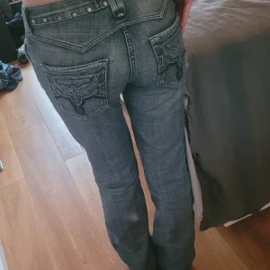 Blå jeans med broderade bakfickor - Säljer ett par blå jeans med snygga broderade bakfickor och nitar i midjan. Använt dem några gånger.