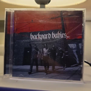 Stockholm Syndrome - Stockholm Syndrome av Backyard Babies är ett energifyllt album med rå attityd och rockiga vibbar. Perfekt för dig som gillar musik med attityd och vill upptäcka klassisk svensk rock. Omslaget har en urban känsla och låtlistan bjuder på starka titlar som Minus Celsius och Earn The Crown.