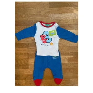 Helt ny pyjamas med gulligt Elmo-motiv från Sesamstraat storlek 50/56 - Helt ny pyjamas med gulligt Elmo-motiv från Sesamstraat (Sesame Street). Originaletikett kvar, aldrig använd. Mjukt bomullsmaterial och tryckknappar vid axeln   Storlek 50/56      