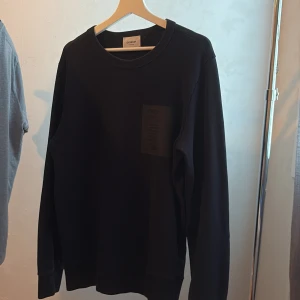 Svart sweatshirt från Dondup - En stilren svart sweatshirt från Dondup med rund halsringning och diskret patch på bröstet. Tröjan har långa ärmar och ribbade muddar vid ärmslut och nederkant. Perfekt för en clean och avslappnad look.