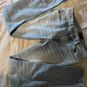 Ljusblå jeans från Tiger of Sweden - Snygga ljusblå jeans från Tiger of Sweden med klassisk femficksdesign. Jeansen har en normal passform och är tillverkade i mjukt denimtyg med subtila slitningar framtill. Perfekta för en avslappnad och stilren look. Modellen heter EVOLVE så slim 