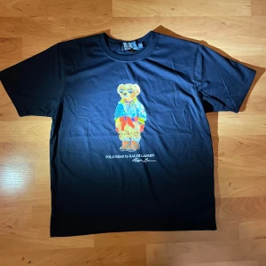 Polo Bear - Polo Bear T-shirt – Marinblå, Storlek M • Helt ny, aldrig använd • Klassisk marinblå färg • Perfekt skick, autentisk Polo Bear-design • Bekväm och snygg för vardagsbruk • Bra pris: endast 24 €!  Köp den innan den är slut! Fråga gärna om du vill ha fler bilder eller detaljer.