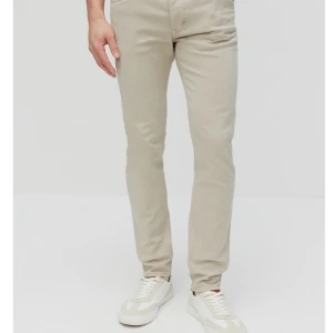 Beige  jeans från Dobber - Snygga beige jeans från Dobber, modell The Editor med tapered fit. Byxorna har klassisk femficksdesign, normal midja och raka ben som smalnar av. Tillverkade i bomull för en skön känsla och stilren look. I skick som ny . 