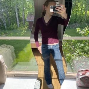 Vinröd topp med spets Gina Tricot - Säljer en vinröd topp från Gina Tricot med v-ringning och fina spetsdetaljer vid halsen. Toppen har lång ärm och sitter snyggt figurnära. Perfekt att styla med jeans eller kjol för en trendig look.