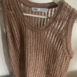Beige stickad linnetopp från Zara - Säljer en beige stickad linnetopp från Zara i storlek M. Toppen är ärmlös och har ett grovmaskigt, luftigt mönster som ger en cool och avslappnad vibe. Perfekt för varma dagar eller lager på lager. Rund halsringning och mjukt material.