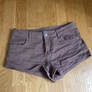 Bruna shorts från H&M - Snygga bruna shorts från H&M i klassisk femficksmodell. De är låga i midjan och har en tight passform. Gjorda i mjuk bomull med lite stretch för extra komfort. Perfekta till sommaren och lätta att matcha med allt. Använda en gång