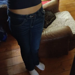 Mörkblå jeans från Gina Tricot 170 - Snygga mörkblå jeans från Gina Tricot i storlek 170. Jeansen har kontrastsömmar, klassiska fickor med lock och knapp bak samt normal passform. Perfekta till vardags med en enkel t-shirt eller hoodie.