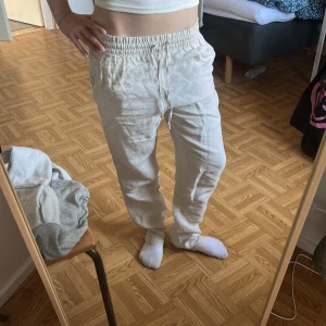 Beiga linnebyxor med snörning - Säljer ett par beiga linnebyxor med avslappnad passform och elastisk midja med snörning. Byxorna har raka ben och sidfickor, perfekta för en chill och luftig stil. Superbekväma och lätta att matcha till olika outfits.