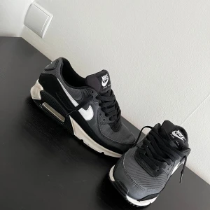 Nike Air Max 90 svart och grå - Nike Air Max 90 sneakers i svart och grå med vita detaljer. Använda ett par gånger men fortfarande i rätt bra skick. Storlek 39