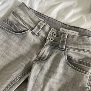 Pepe jeans - Säljer ett par gråa jeans från Pepe jeans i modellen Venus. Byxorna har rak passform, låg midja och dubbla knappar framtill. köpte dem på plcik men säljer då de va för stora. storlek 28 i midjan💓 