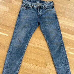 Diesel Larkee-Beex jeans i blå denim - Säljer ett par klassiska blå jeans från Diesel, modell Larkee-Beex. Jeansen har regular-tapered passform, fem fickor och snygga slitningar. Perfekta för dig som gillar en tidlös stil med modern touch. Strl 31-30