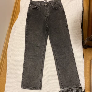 Grå jeansbyxor från NA-KD - Säljer ett par grå jeansbyxor från NA-KD med klassisk femficksdesign och raka ben. Byxorna har hög midja och stängs med knapp och dragkedja. Perfekta till en avslappnad stil.