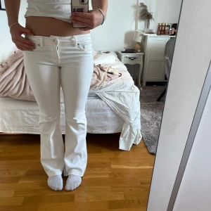 Vita bootcut jeans från H&M Divided - Säljer ett par vita bootcut jeans från H&M Divided i storlek 38. Byxorna har låg midja, klassisk femficksdesign och stängs med dragkedja och knapp. Helt oanvända!