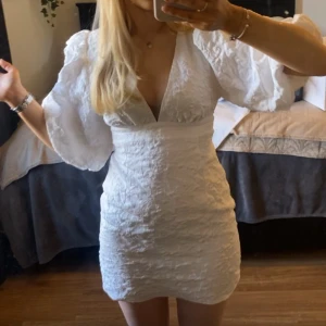 Vit kortklänning med puffärmar - Säljer denna populära showpoo klänningen som är perfekt för studenten. Den är aldrig använd med prislapp kvar💕