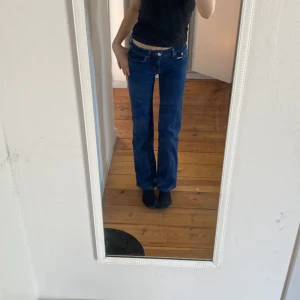 Blå jeansbyxor från 157 - Säljer ett par klassiska blå jeansbyxor från 157 med normal passform och raka ben. Byxorna har fem fickor, knäppning med dragkedja och knapp samt snygga kontrastsömmar. Perfekta till vardags och enkla att matcha med olika toppar.