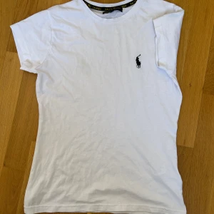 Ralph lauren t shirt - Vit t-shirt från Ralph Lauren med ett märke på bröstet. Den var för liten för mig och därav säljer jag den.                                                                        Pris kan sänkas vid snabb affär