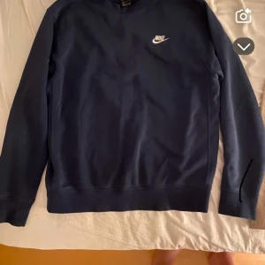 Mörkblå sweatshirt från Nike - Säljer en stilren mörkblå sweatshirt från Nike med klassisk logga på bröstet. Tröjan har rund halsringning och långa ärmar. Perfekt för en sportig och avslappnad look.