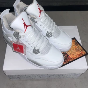 Vita Nike Air Jordans med röda detaljer - Säljer ett par fräscha vita Nike Air Jordans med röda detaljer och klassisk Jumpman-logga. Skorna har snörning, platt sula och rund tå. Perfekta för dig som vill sticka ut med stilrena sneakers.