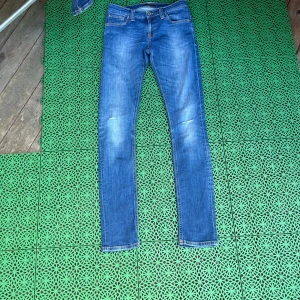 Blå skinny jeans - Säljer ett par blåa nudie jeans. Sköna slitningar vid knäna. Pris kan diskuteras. Skriv om du vill ha mer bilder m.m storlek 27/32