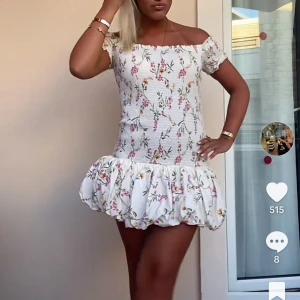 Blommig kortklänning med volang - Supersöt kortklänning med blommigt mönster i rosa och grönt på vit botten. Klänningen har offshoulder-modell, smockad överdel och volangig kjol. Perfekt för sommarens alla tillfällen! Storlek M men sitter som en xs/s💓skicka prisförslag!