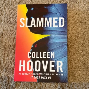 Slammed (oanvänd) - Säljer boken 'Slammed' av Colleen Hoover. Omslaget har en färgstark design med en fjäril i blått och svart mot en orange bakgrund. Boken är på engelska och är en pocketutgåva. Perfekt för dig som gillar romantik och känslosamma berättelser.